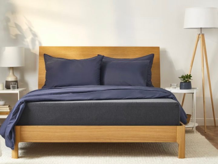 A Casper mattress sits on a wood bed frame in a bright bedroom.