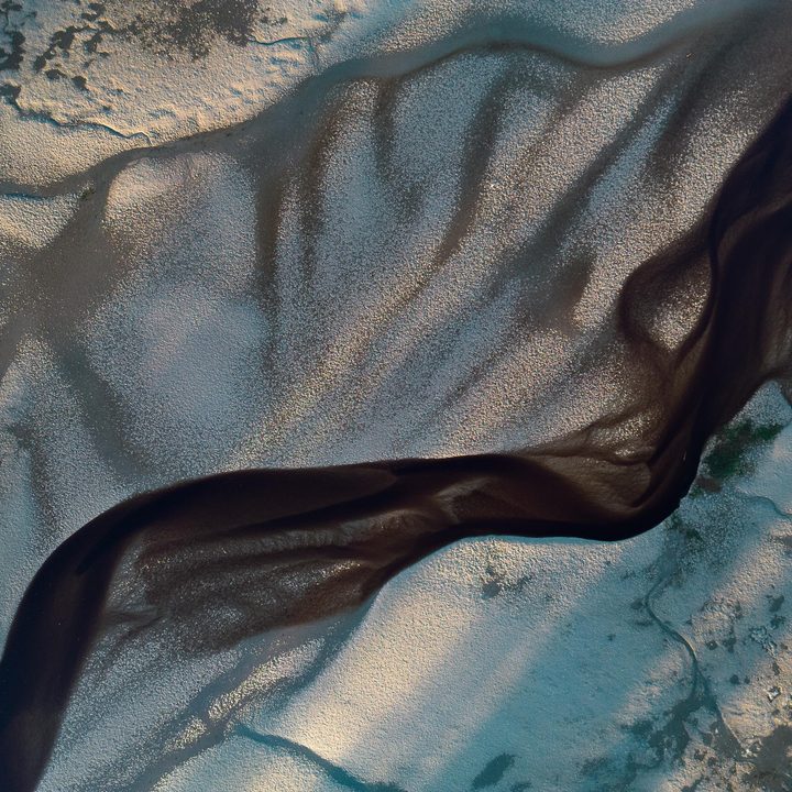 Braided pattern of a stream running through a sandy shore.