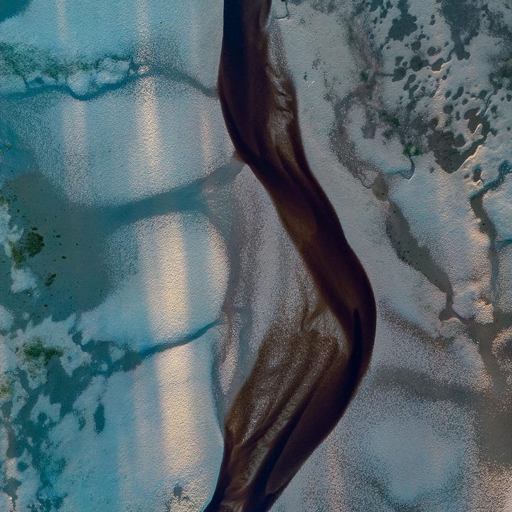 Braided pattern of a stream running through a sandy shore.