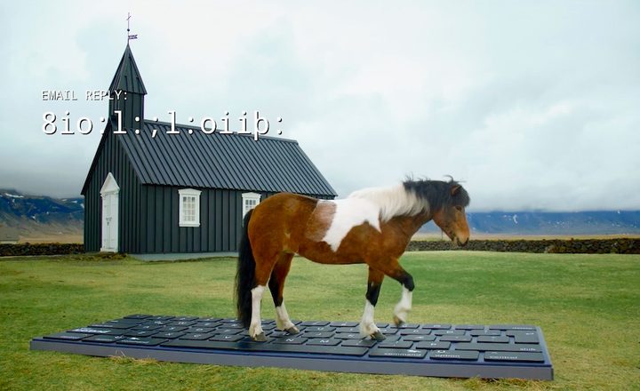 A horse writing an email using a giant keyboard.