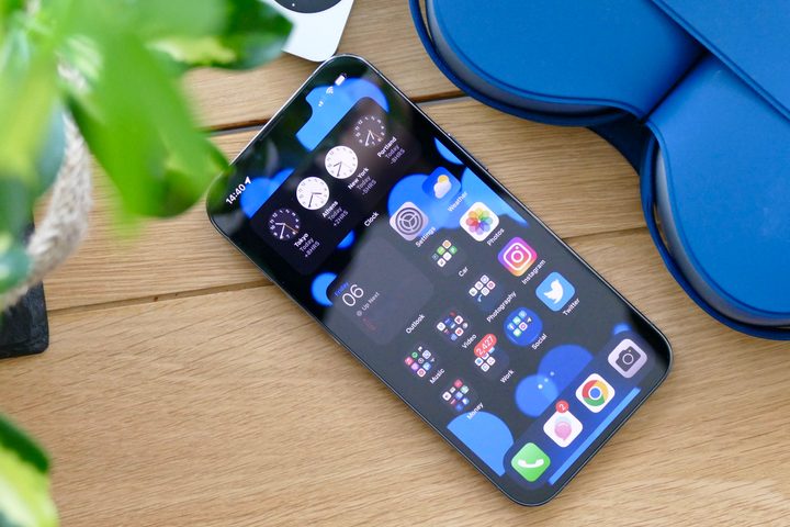 iOS Home screen shown on an iPhone 13 Pro, resting on a desk.