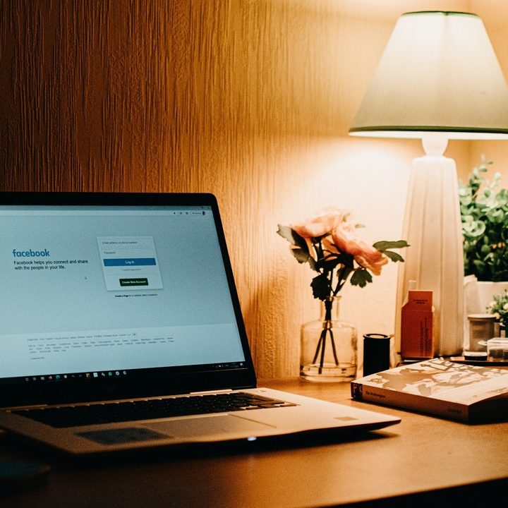 A laptop on a desk with Facebook's website on its screen.