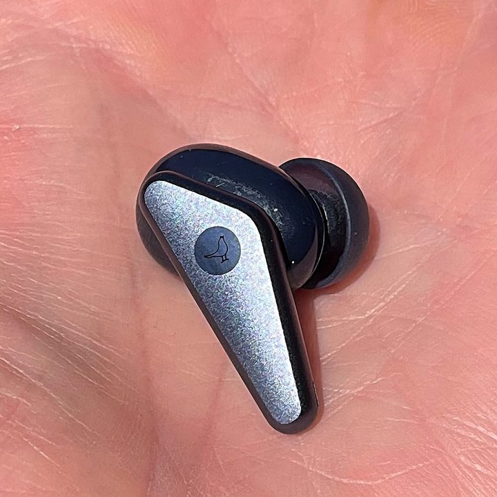 Single Earbud closeup in palm of hand.