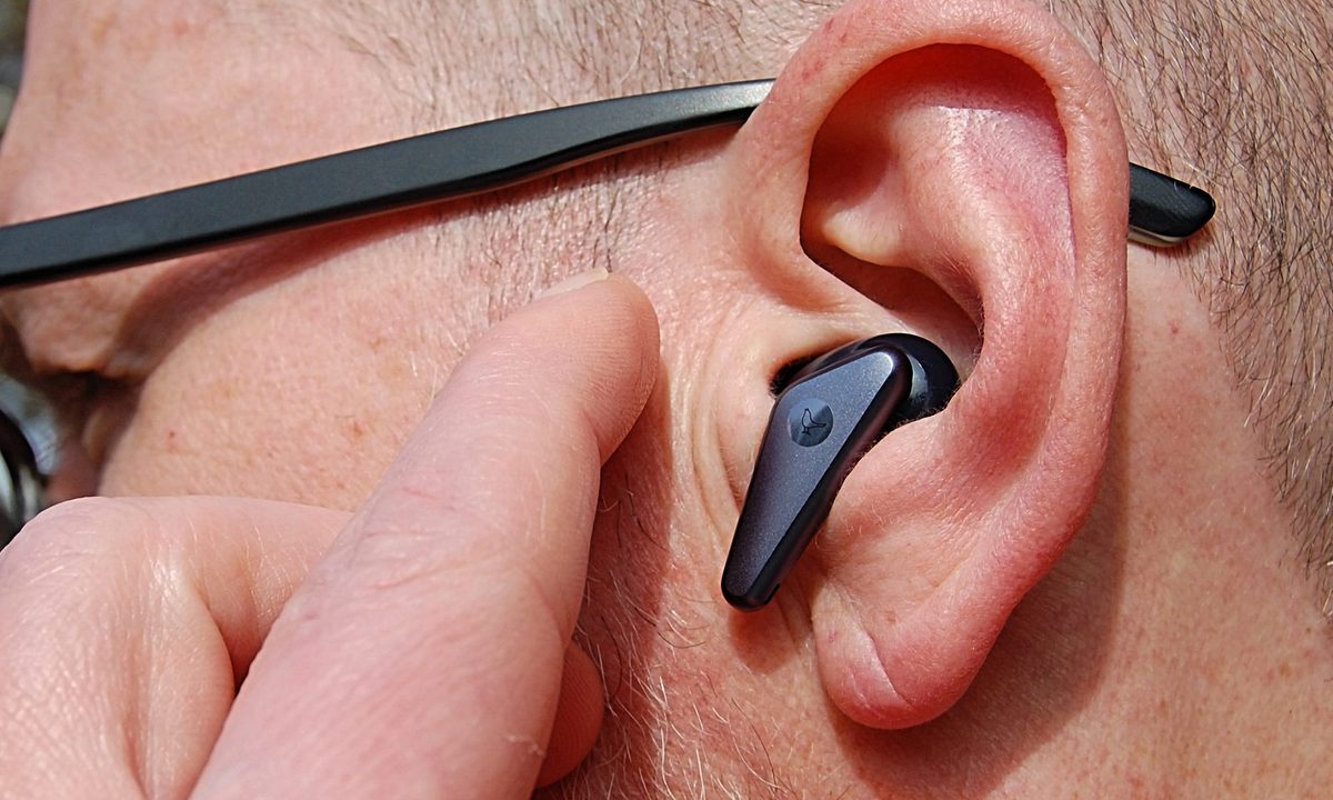 Wireless earbud in ear about to be tapped.