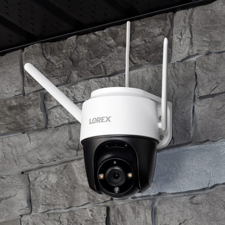 Lorex 2K Pan-Tilt Wi-Fi Outdoor Security Camera mounted on stone wall.