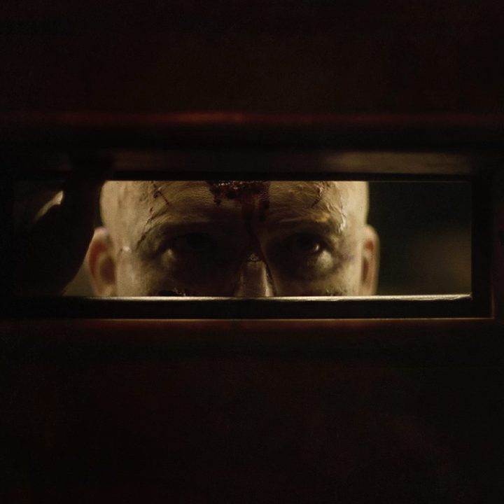 Rory Kinnear's character stares through a door's mail slot in a scene from Men.