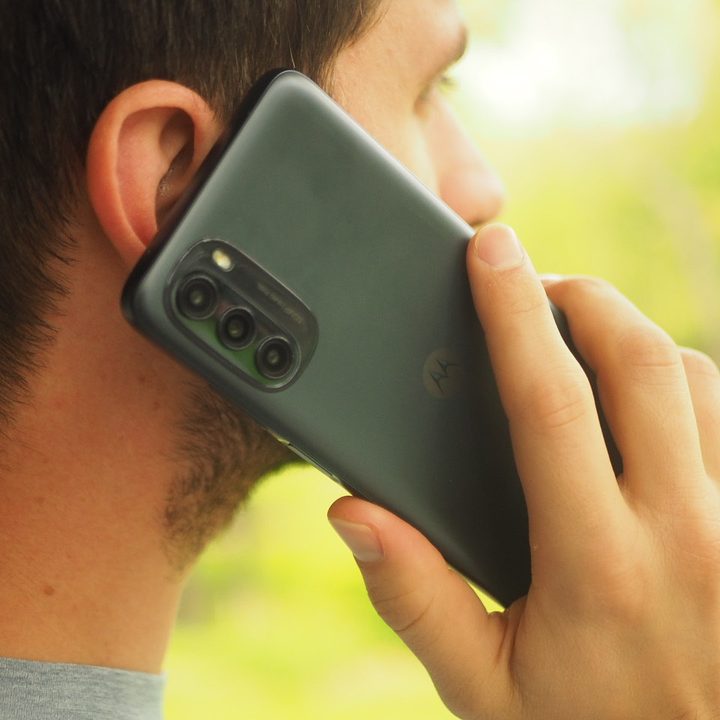 A person holding a Moto G 5G smartphone up to their ear