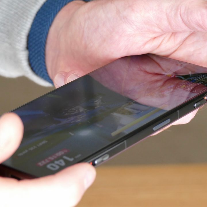 Man holding the Poco F4 GT and using its shoulder buttons.