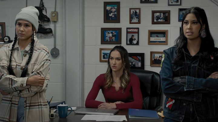 Keilani Elizabeth Rose, Tasya Teles, and Blair Lamora stare at the camera near a desk in a scene from Shoresy.