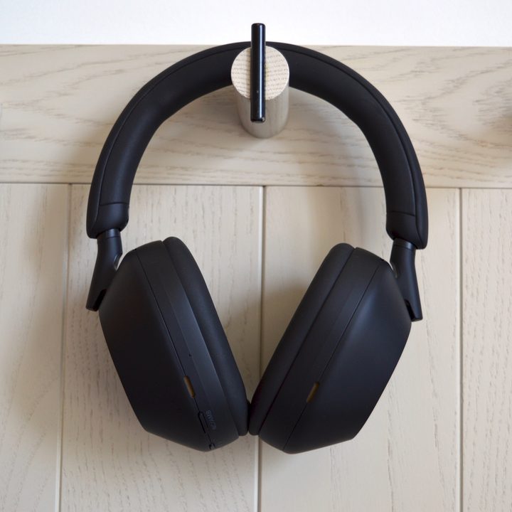 Sony WH-1000XM5 wireless headphones hanging on wall hook.