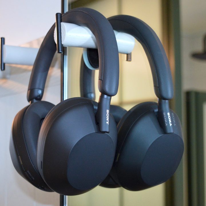 Sony WH-1000XM5 wireless headphones hanging on wall hook in front of a mirror.