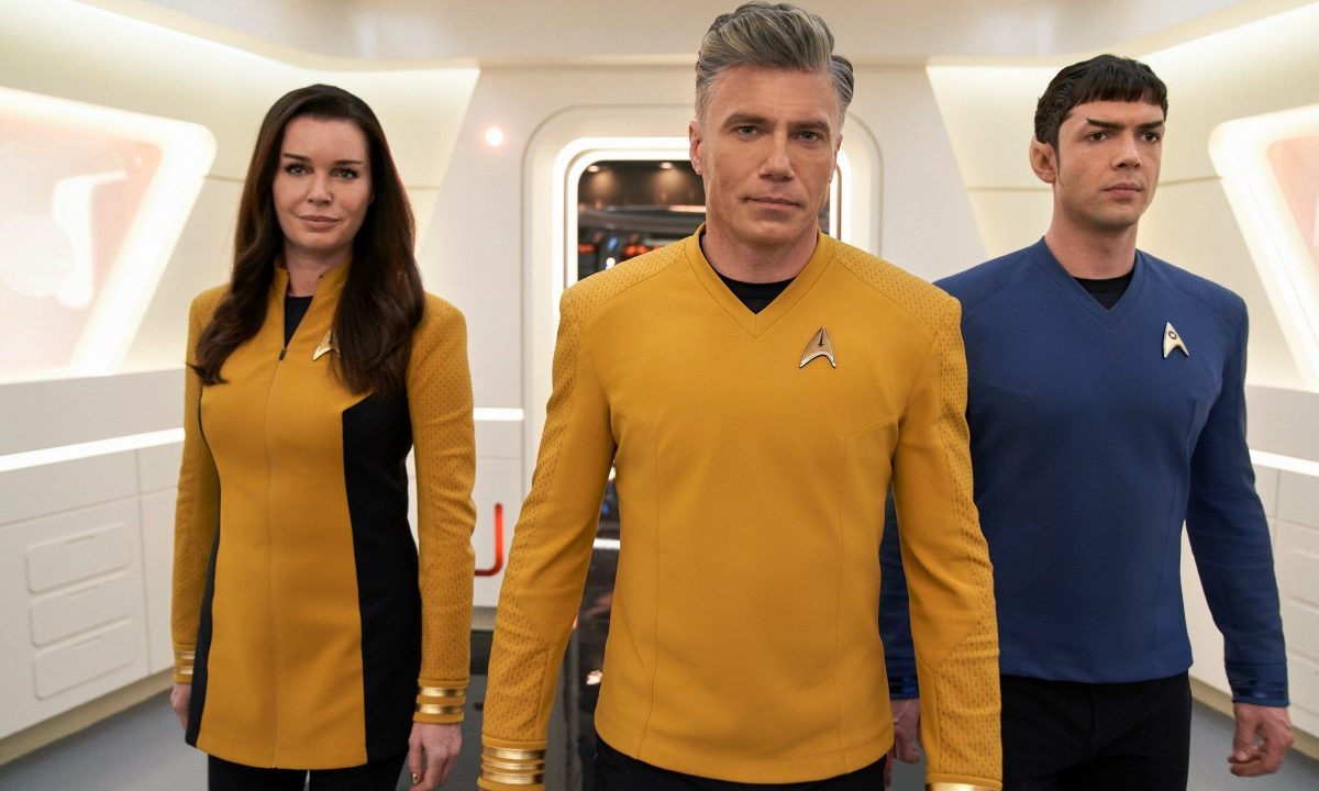 Rebecca Romijn, Anson Mount, and Ethan Peck walk in the hallway of the USS Enterprise in a scene from Star Trek: Strange New Worlds.