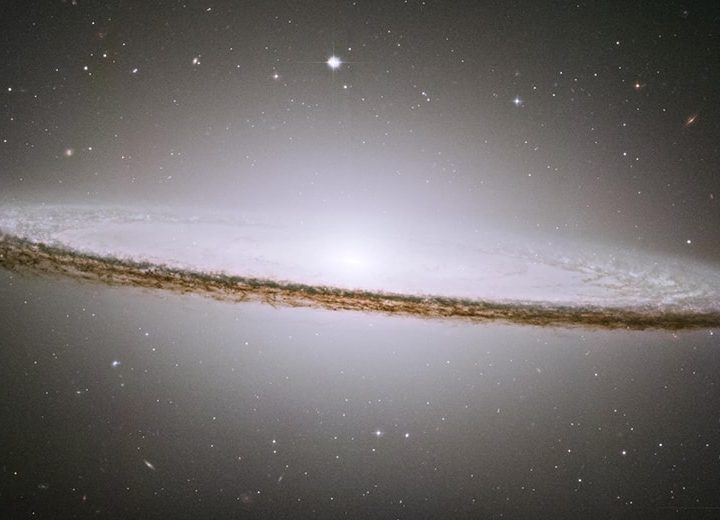 The Sombrero galaxy, Messier 104 (M104). The galaxy's hallmark is a brilliant white, bulbous core encircled by the thick dust lanes comprising the spiral structure of the galaxy. As seen from Earth, the galaxy is tilted nearly edge-on. We view it from just six degrees north of its equatorial plane. This brilliant galaxy was named the Sombrero because of its resemblance to the broad rim and high-topped Mexican hat.