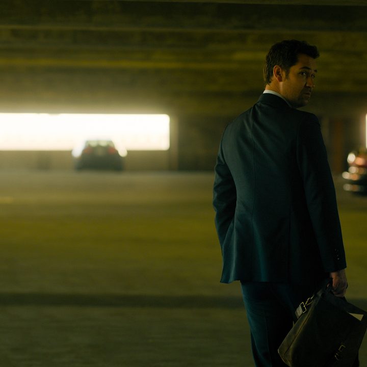 Mickey Haller walking in a parking garage in a scene from The Lincoln Lawyer.