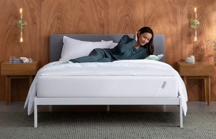 This is an image of a model reading a book on a Tuft and Needle mattress.