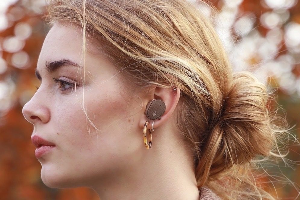 Woman wearing Yamaha TW-E5B earbuds in brown.