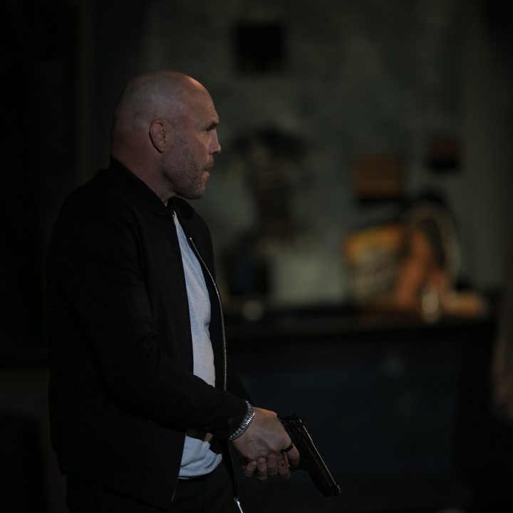 Randy Couture holds a gun in a scene from Blowback.