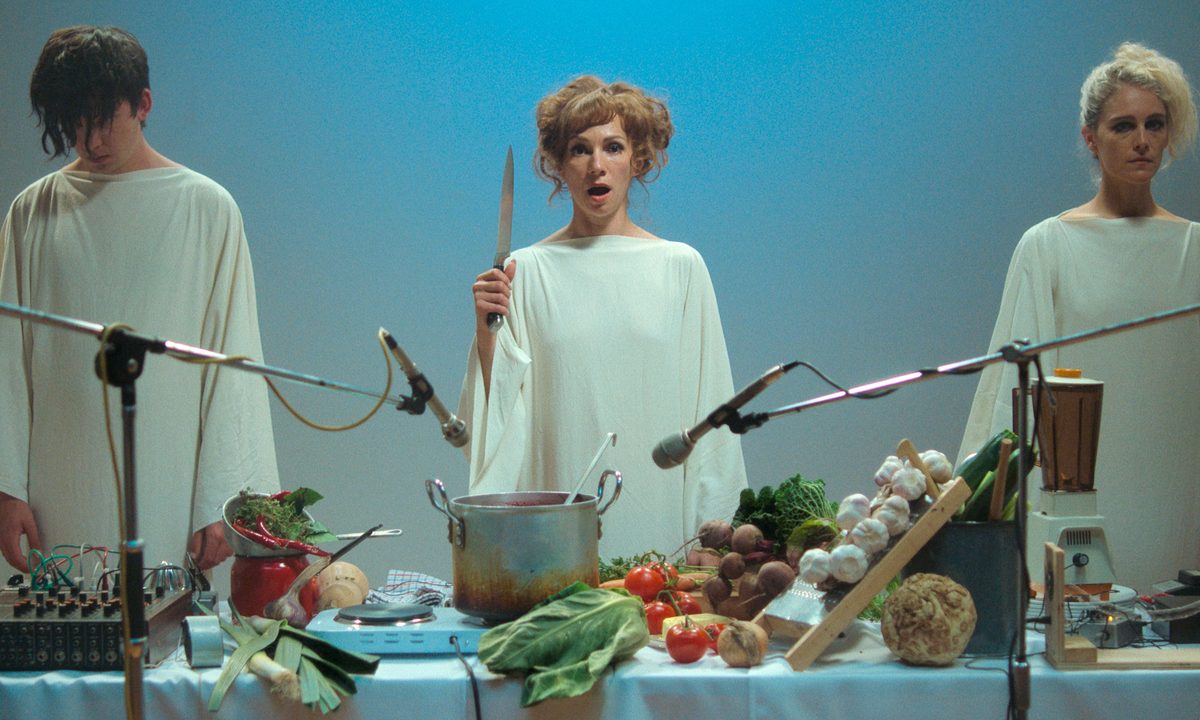 Billy, Elle, and Lamina stand in front of a banquet table together in Flux Gourmet.