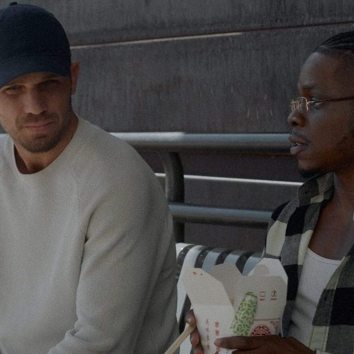 Cam Gigandet sitting on a bench next to someone in a scene from Blowback.