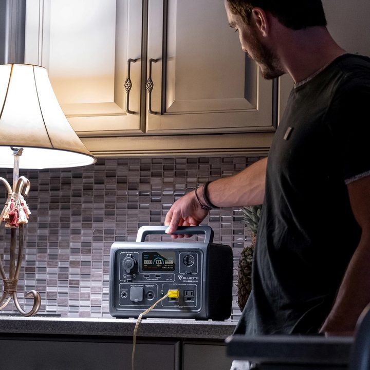 A man powers a lamp in a kitchen during a power outage with a Bluetti EB3A.