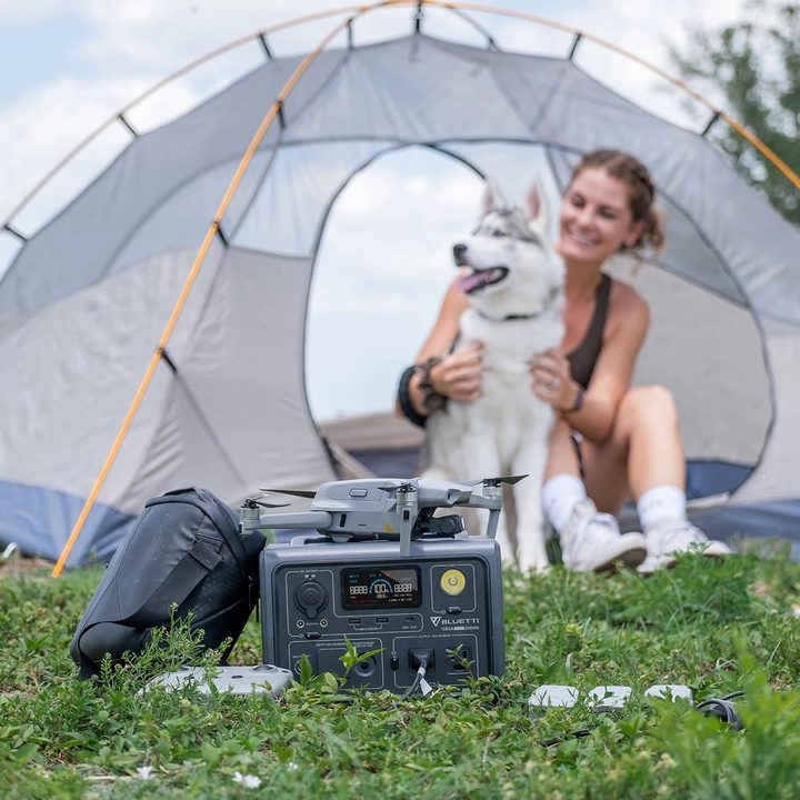 A woman uses Bluetti EB3A used while camping with her dog.