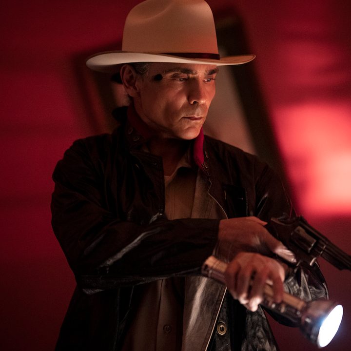 Joe Leaphorn holding a gun and flashlight in a scene from Dark Winds.
