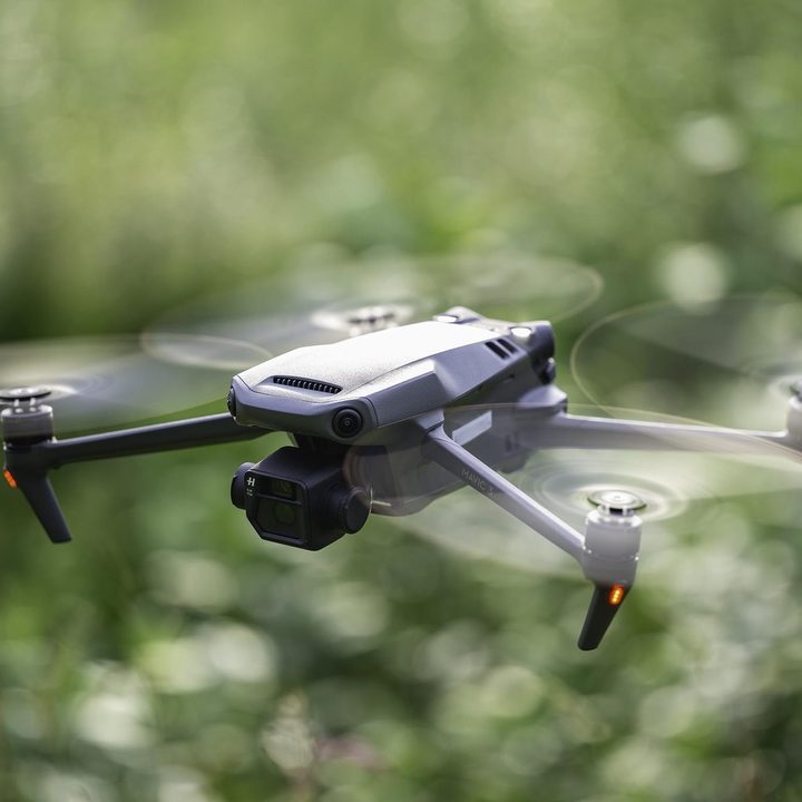 The DJI Mavic 3 in flight with a blurred green background.