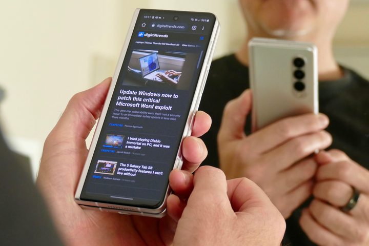 Man holding a Galaxy Z Fold 3 showing a browser window on the outer screen.