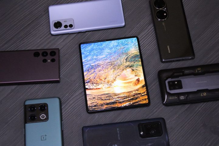 Galaxy Z Fold 3 inner display alongside other flagship phones on a table.