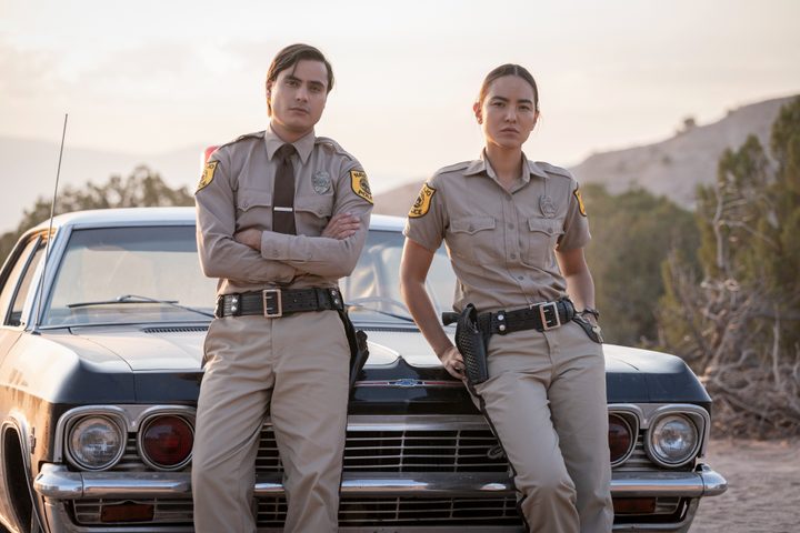 Jim Chee and Bernadette Manuelito lean against a car in Dark Winds.
