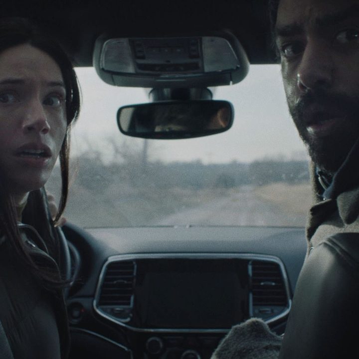 Katie Parker and Rahul Kohli sitting in a car in a scene from Next Exit.