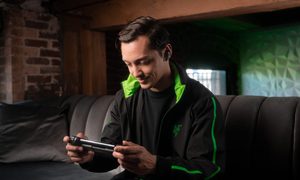 A man plays a Razer Kishi V2 on his couch.