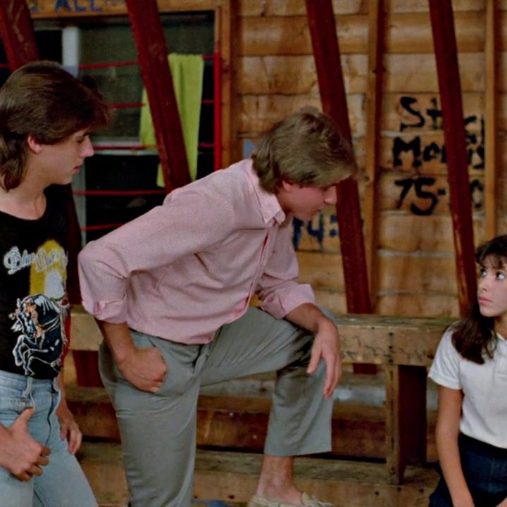 Two male campers are talking to a seated female camper from the movie Sleepaway Camp.