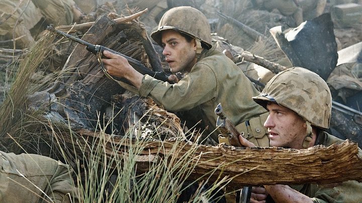 Rami Malek and Joseph Mazzello point guns and cover in The Pacific.