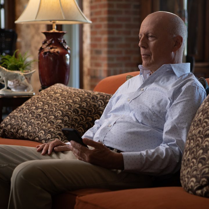 Bruce Willis sitting on a couch in a scene from White Elephant.