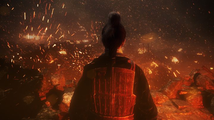 A soldier in red looks over a burning village.