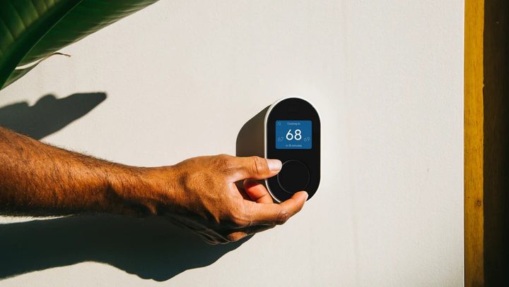 Person adjusting Wyze Thermostat using temperature wheel.