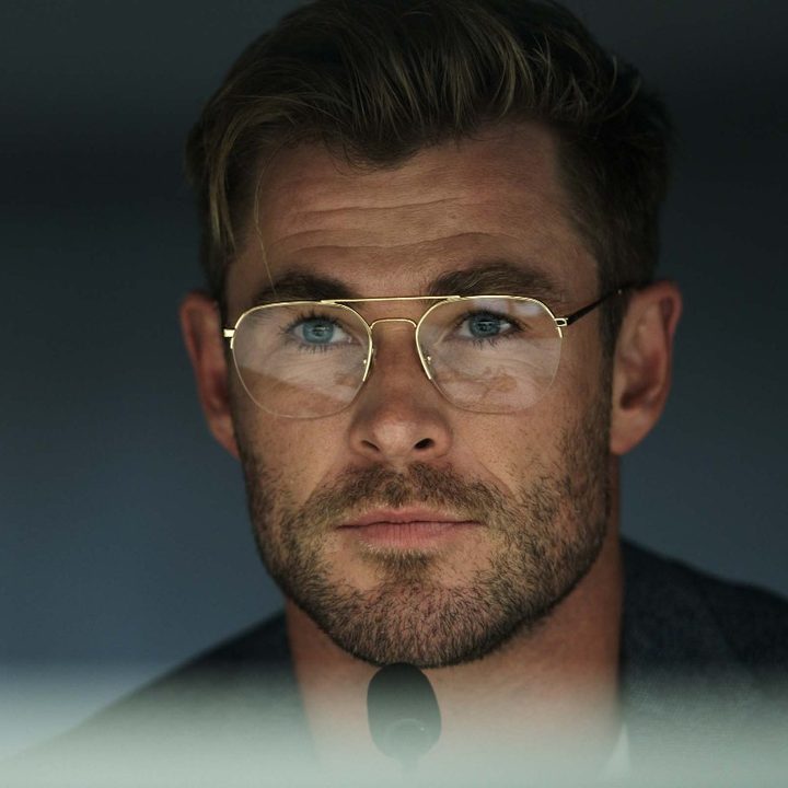 Chris Hemsworth smirks in front of a mi crophone in a scene from Spiderhead.