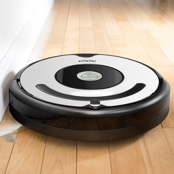 An iRobot Roomba 670 robot vacuum picks up dust on a hardwood floor.