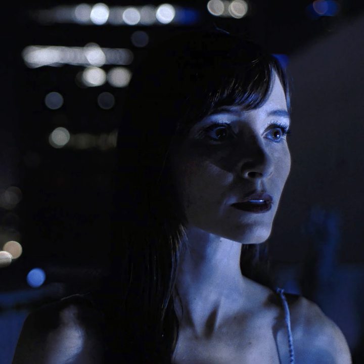 A woman stands outside in a city inImmortality.