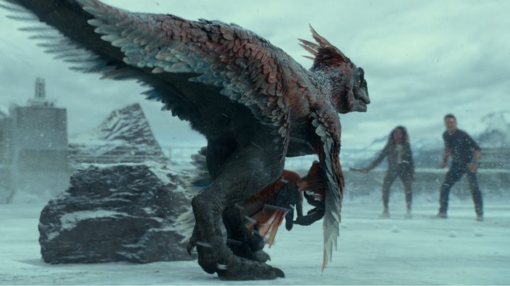 A dinosaur approaches two characters on the ice in a scene from Jurassic World: Dominion.