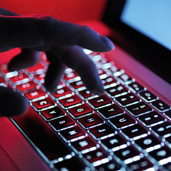 A dark mystery hand typing on a laptop computer at night.