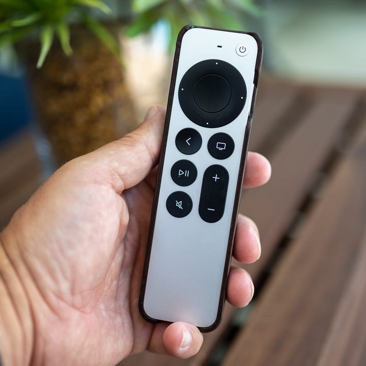 Person holding apple TV remote in their hand.
