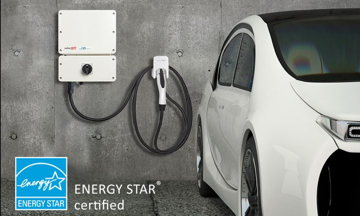 SolarEdge inverter mounted on wall next to an EV and charging cable.