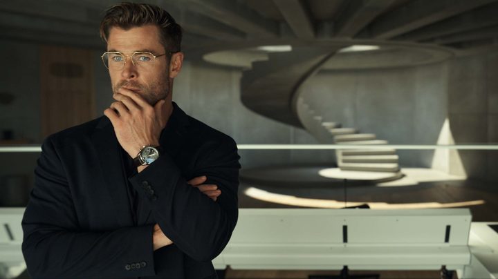 Chris Hemsworth stares through a large glass window in a scene from Spiderhead.