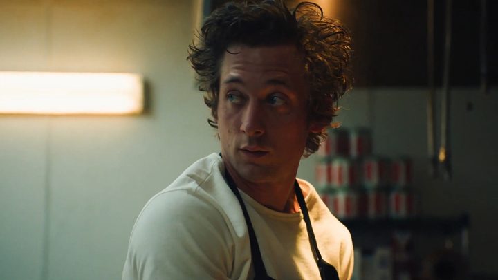 Carmen from FX series The Bear in his apron, looking back.