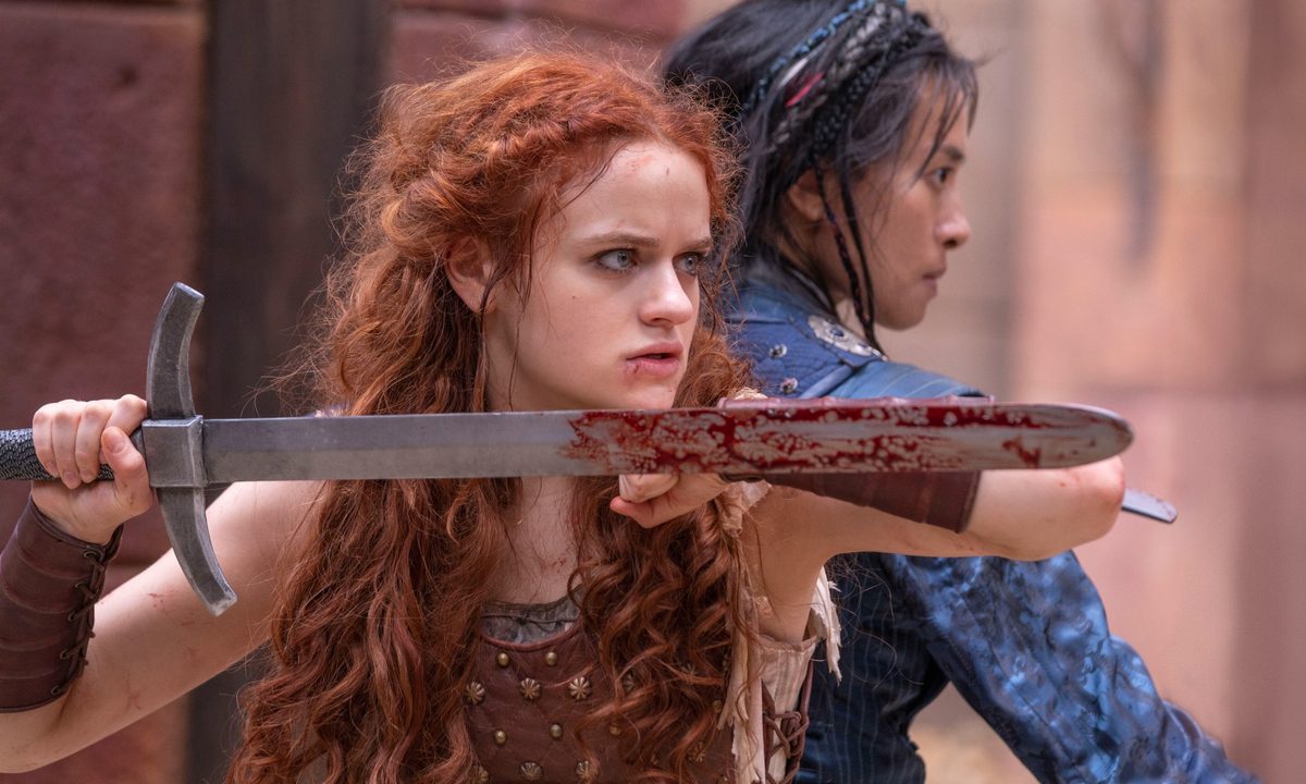 Joey King and Veronica Ngo stand back to back with swords in a scene from The Princess.