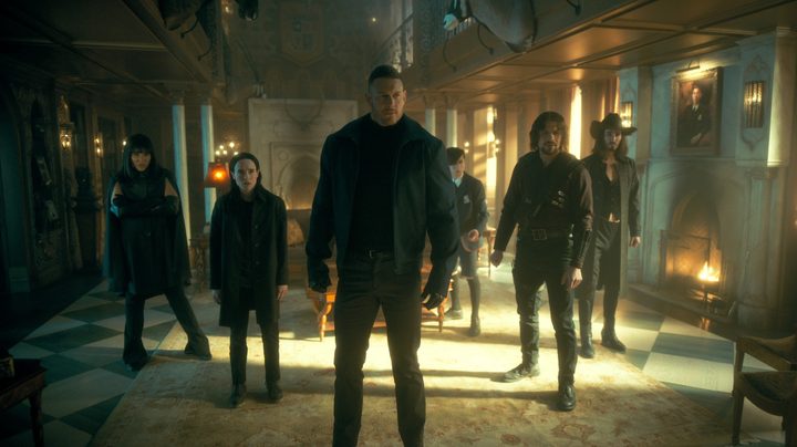 The cast of The Umbrella Academy stands together in the main room of the family mansion.