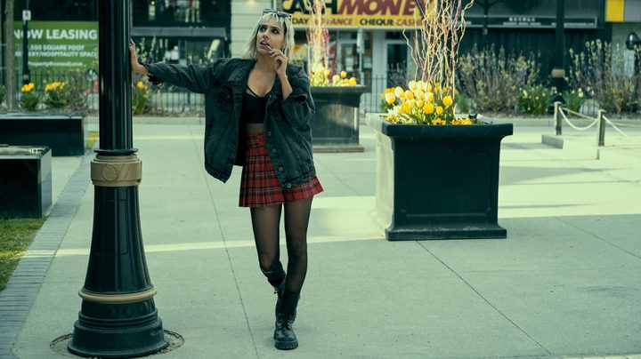 Ritu Arya leans against a streetlight in a scene from season 3 of The Umbrella Academy.