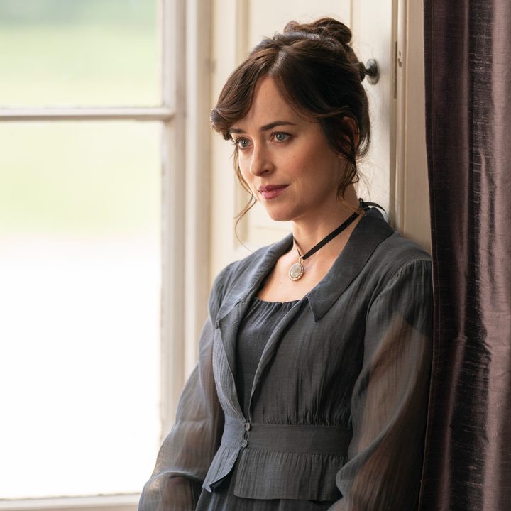 Anne Elliot stands near a window and drapes in Netflix's Persuasion.